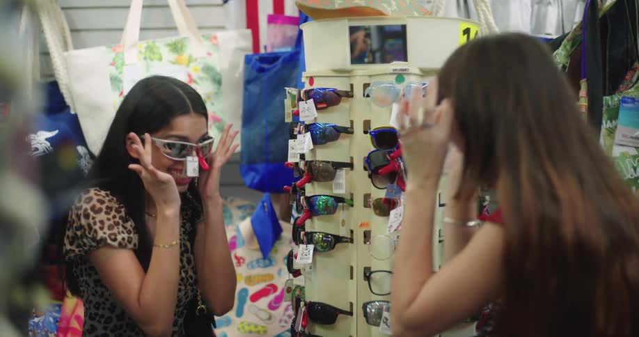 Two friends inside a store having fun trying on sunglasses
