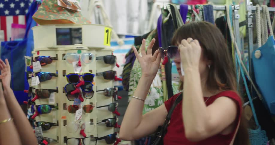 Two young women in a store at night trying on sunglasses and having fun