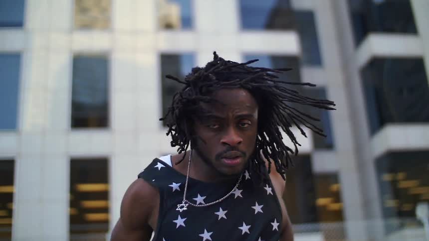 A man is dancing outside near a tall building