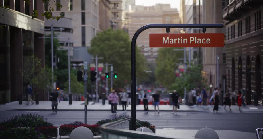 A shot focuses on a martin place sign in an urban setting with people walking in the background and city buildings visible