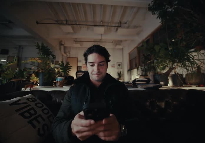 Man sitting in an armchair typing on a smartphone