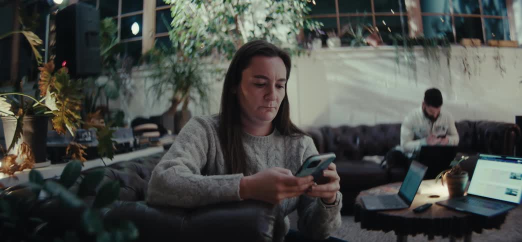 Man and woman sitting in the living room at night both use their smartphones