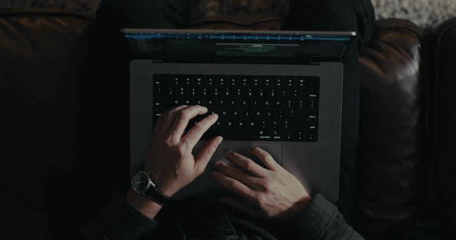Hands of a person sitting in an armchair typing on a laptop