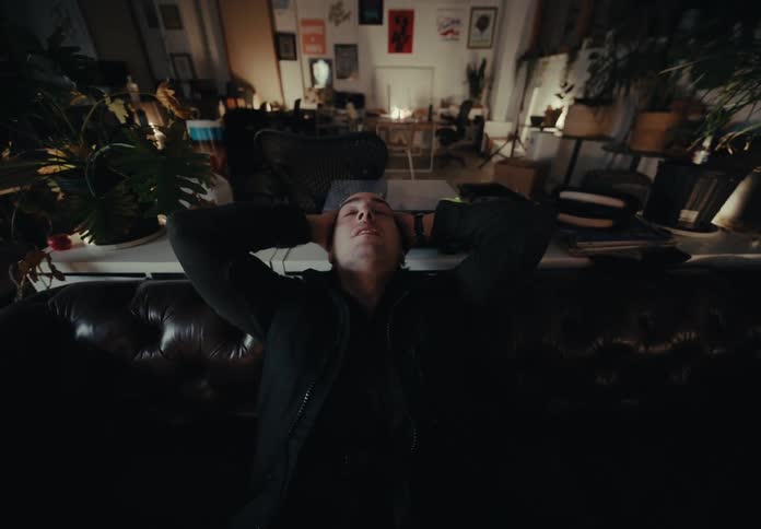 A man puts his phone down and leans back into the couch