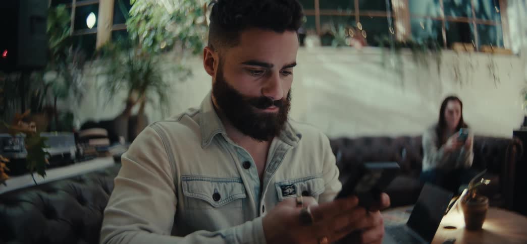 Man and a woman sitting in an armchair typing on a smartphone