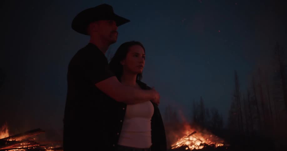 A man hugs a woman as they watch the flames burn