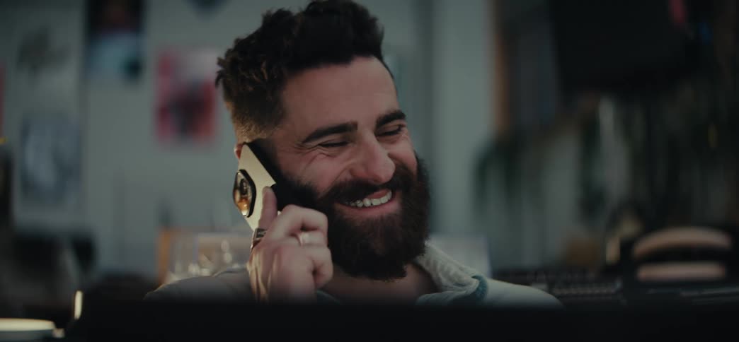 Portrait of a happy bearded man sitting and talking on a phone call