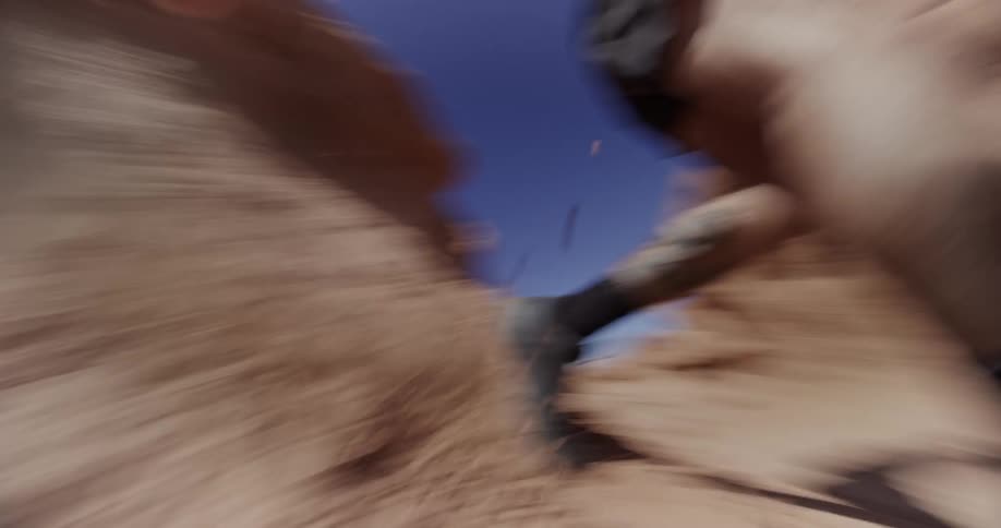 A person is jumping and running in a rocky desert landscape with clear blue skies