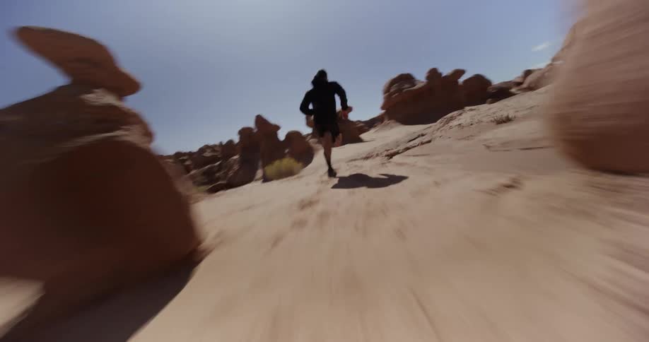 Person running quickly through a desert environment with rock formations