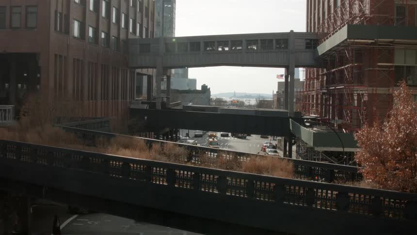 Vehicles and pedestrians travel beneath pedestrian bridges in a city