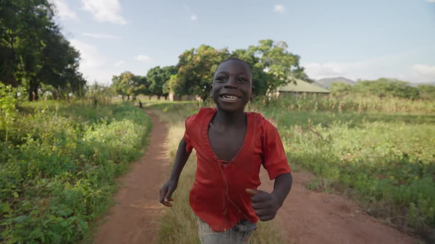 Happy smiling boy running through a field