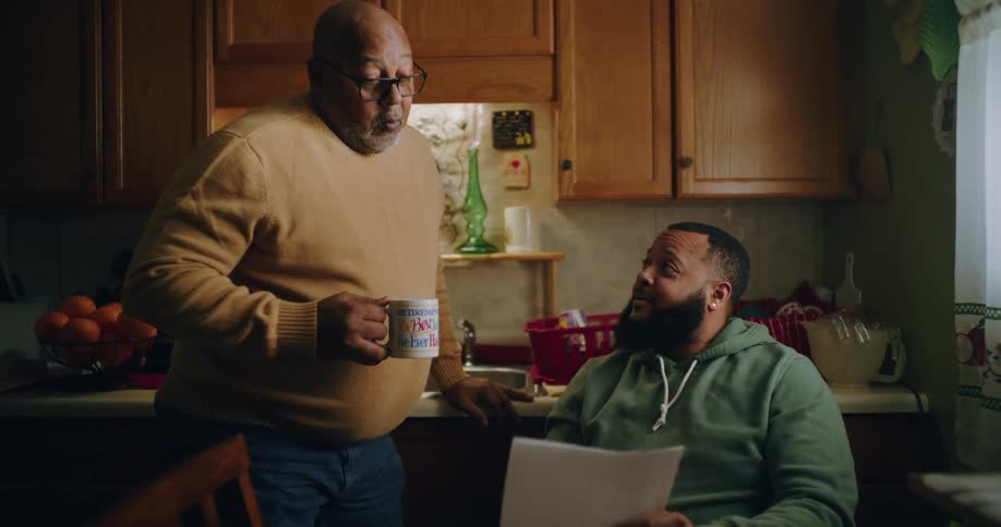 Father and son reviewing documents in a cozy kitchen