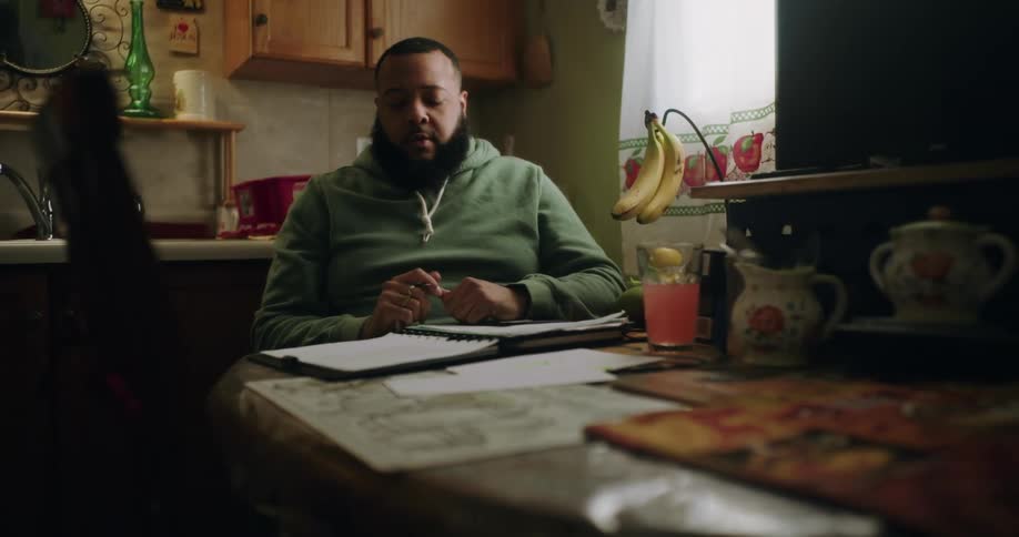 Man sitting at a table thoughtfully and writing in a notebook