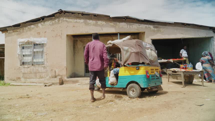 Man removing rope from top of small car parked next to a house