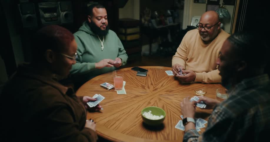 Four people sitting at a table playing cards