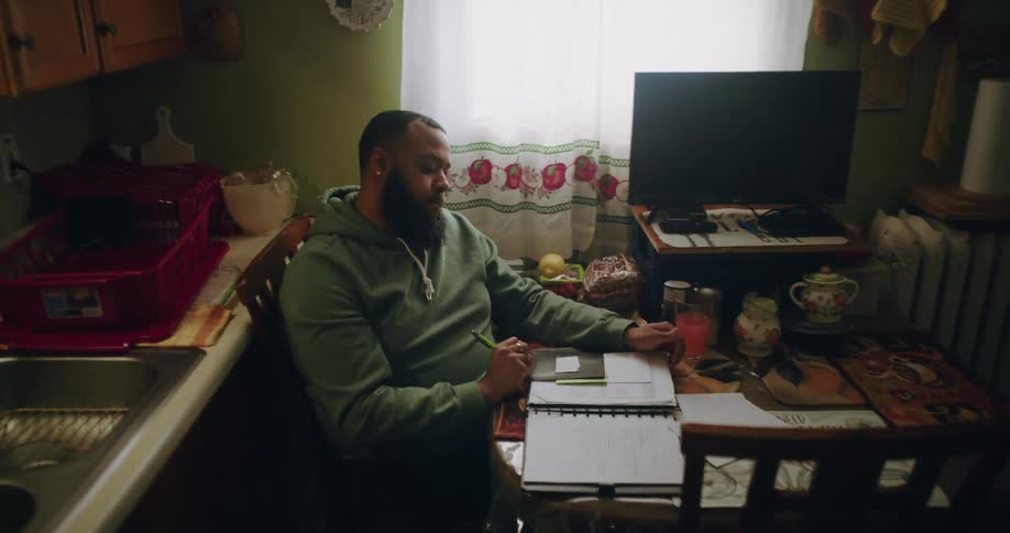 Man sitting at a table writing thoughtfully