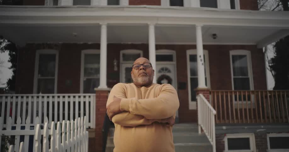 A man crosses his arms in front of the home