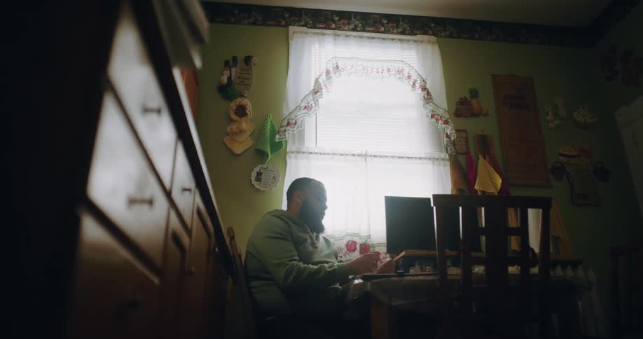 Man sitting at a table in the kitchen writing