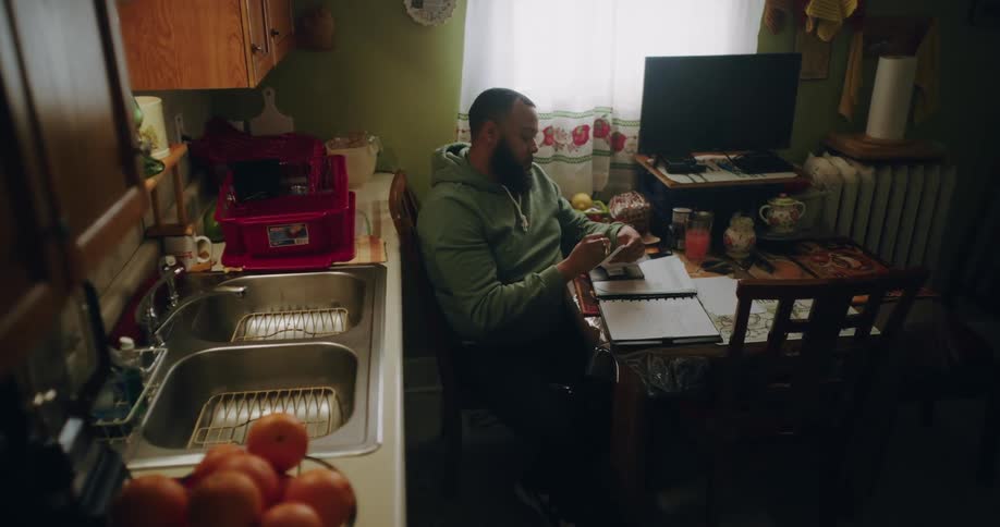 Man sitting at kitchen table writing in a notebook