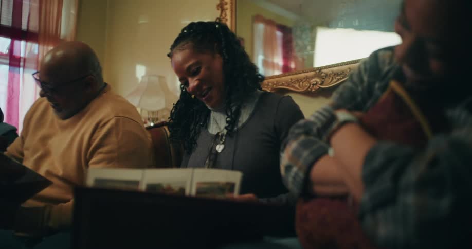 Three people sitting on the couch laughing while looking at photos