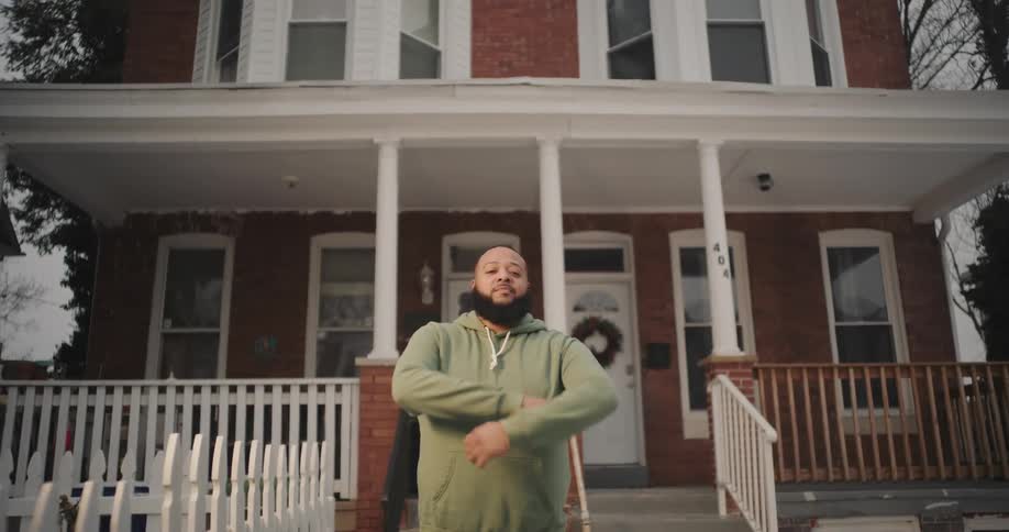 Man crossing his arms as he stands in the yard in front of a house