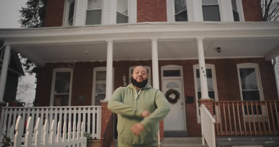Portrait of a man in front of a house crossing his arms