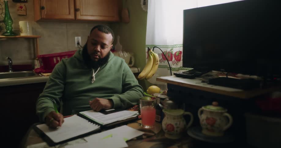 Man sitting at a table in the kitchen writing in a notebook