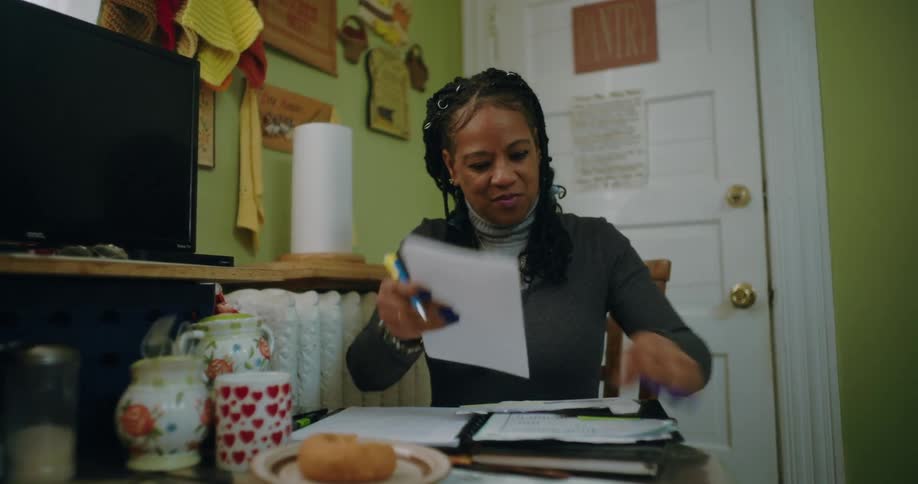 A woman is doing paperwork at her kitchen table
