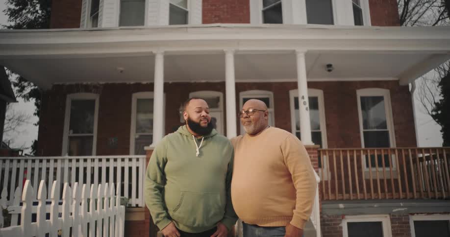 Father and son hugging while standing outside a house