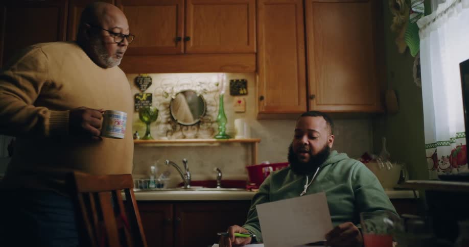 A man drinks coffee and talks with another man at the table