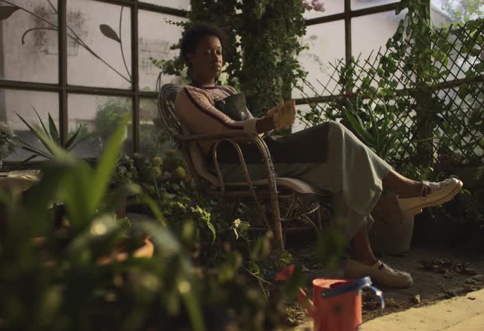 A woman sits down in her greenhouse