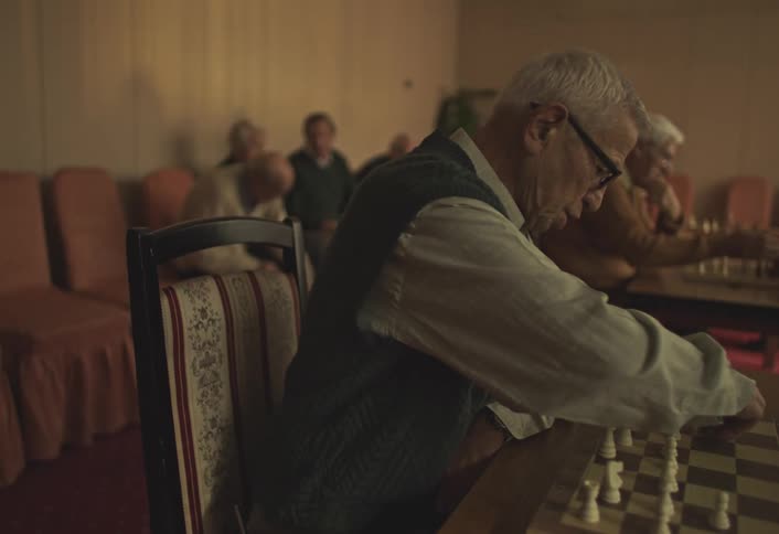 Elderly men sitting at a table playing chess