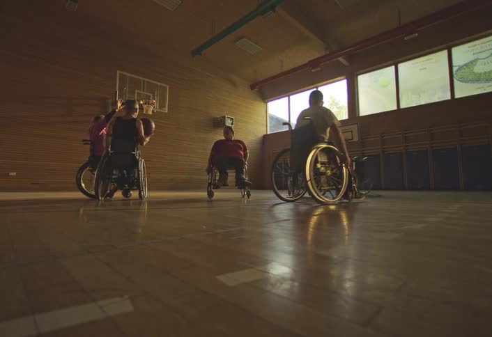 People in wheelchairs bounce the basketball and shoot during a game