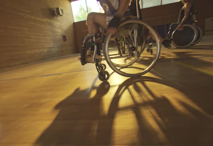 People in wheelchairs are having a very competitive game of basketball