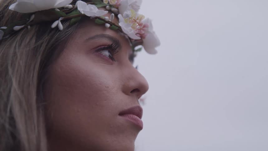 A woman is wearing a flower covered head wreath