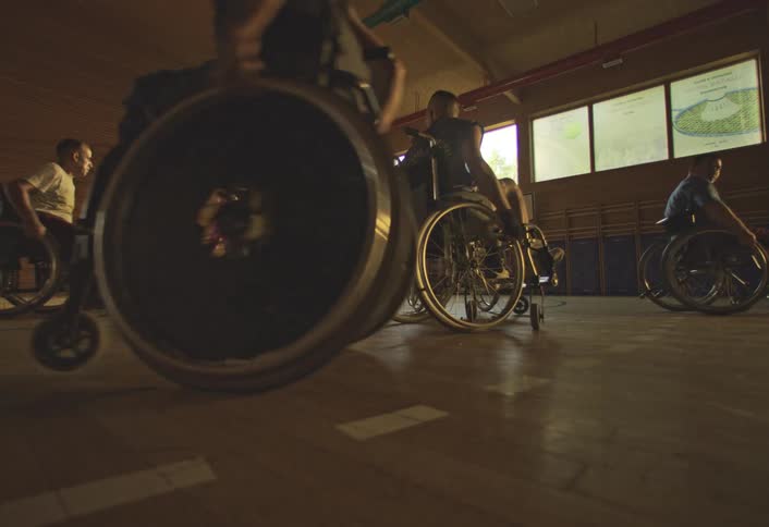 Group of wheelchair users playing basketball on an indoor court