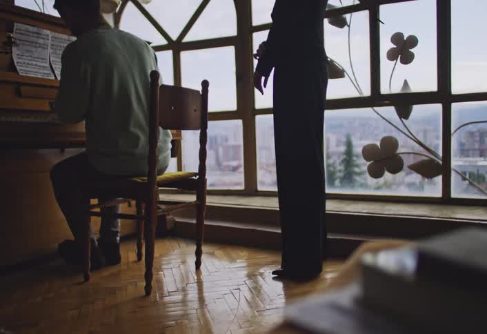 A man is playing the piano by the window