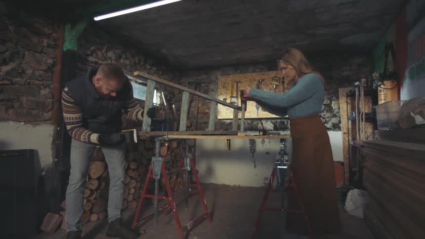 Woman and man carpenters working on the same object in a workshop