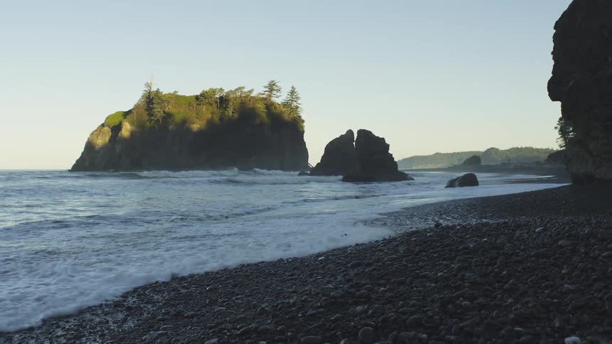 A rocky coastline scene with a prominent sea stack in the ocean