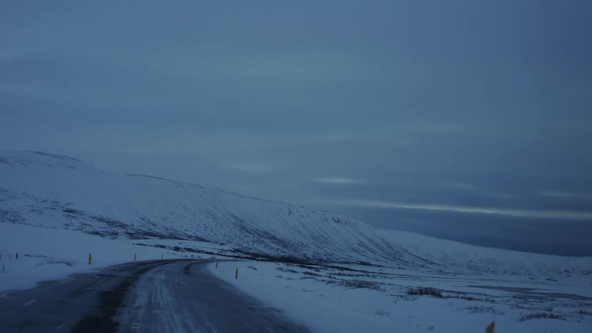Moving view of a paved road surrounded by snowy mountains