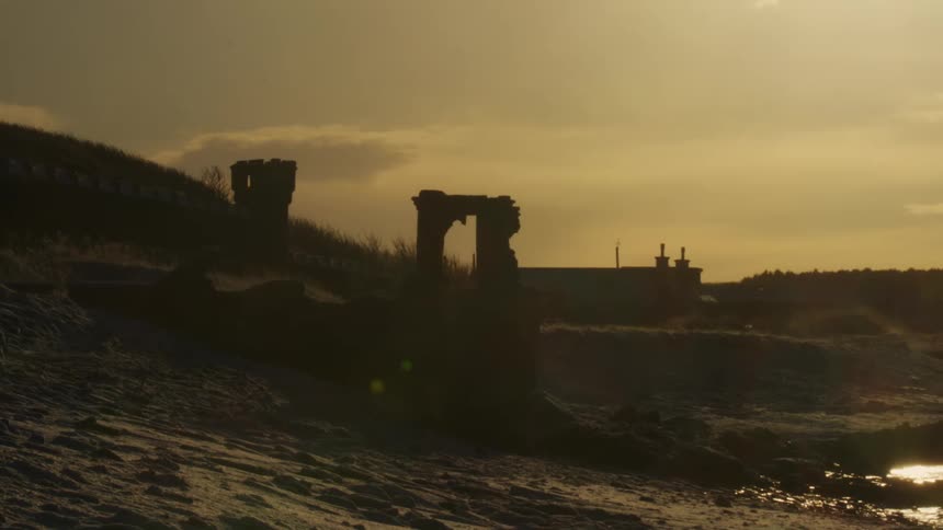 Sand and ruins on the edge of a beach at dawn