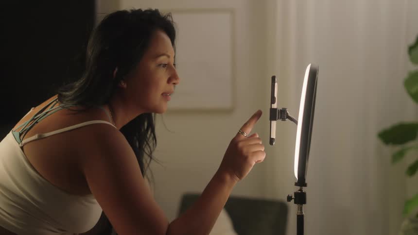 Woman clicking on a smartphone screen on a tripod in the living room