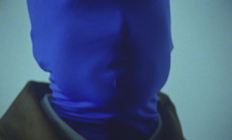 Person with hood covering face and gloves of the same blue color with hands together