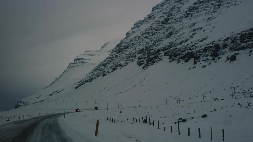 Road with some traffic on the edge of a snowy mountain