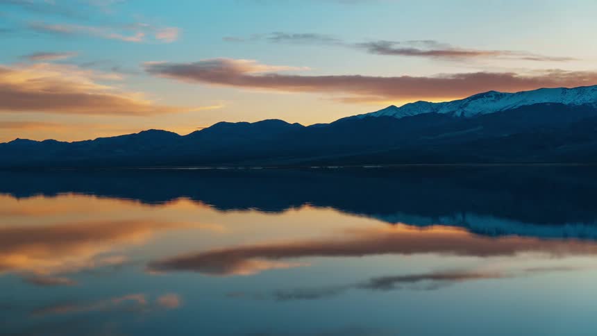 Landscape of a lake reflecting the dawn sky and surrounded by mountains