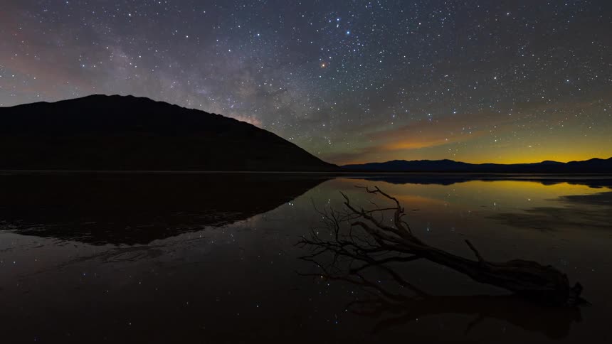 Night landscape with a starry sky reflected in the water mountains in the background