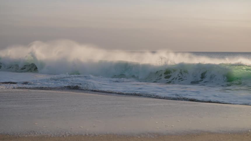 A large wave crashes on the beach