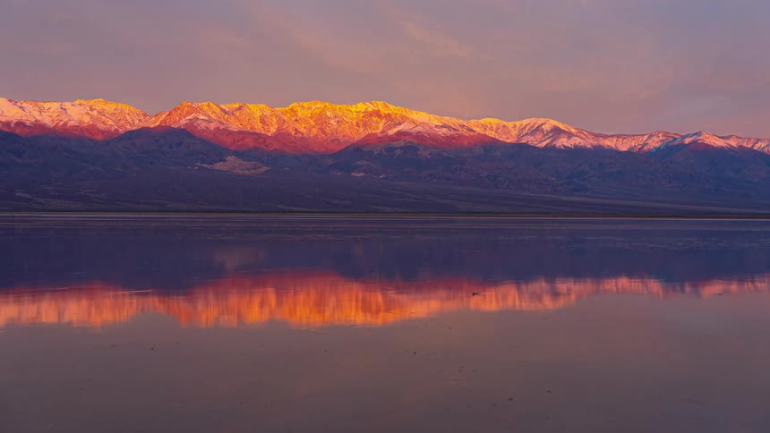 A snow covered mountain is by the lake