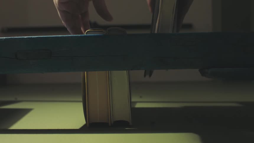 Pair of hands placing two books on a bookshelf