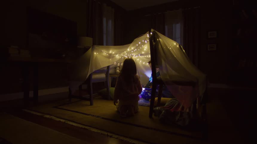 Children play under the blanket tent